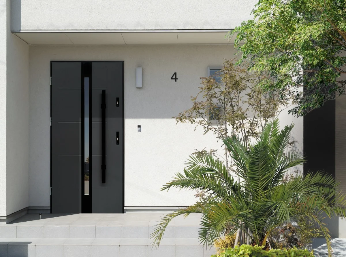 Minimalistyczne drzwi stalowe do domu otoczone subtelnymi roślinami i elegancką fasadą.
